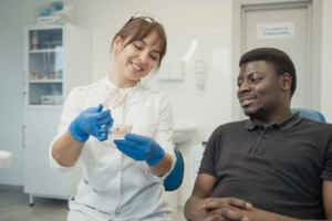 A female Caucasian dentist showing a dental cast to a black male patient