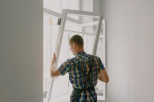 A Caucasian man installing a white, glass window